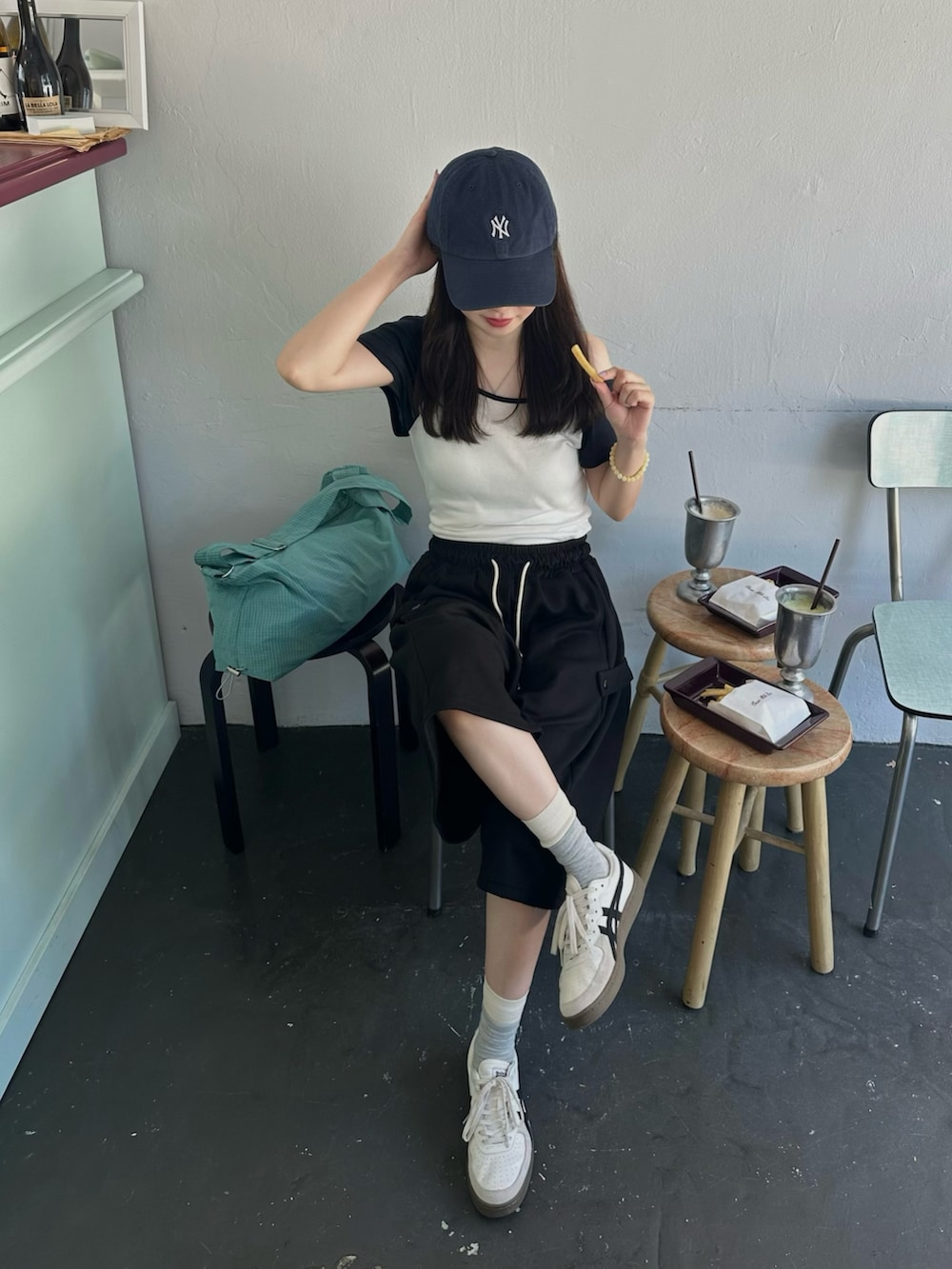 ホワイト系のスニーカー、ホワイト系のTシャツ/カットソー、ブラック系のパンツを着用したレディースの夏コーディネートの2枚目の写真
