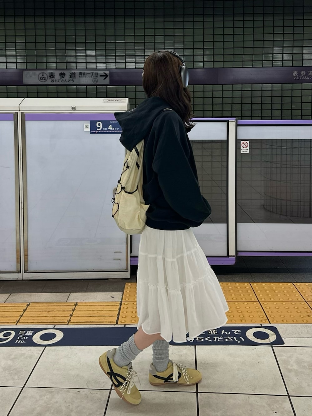 ブラック系のパーカー、ホワイト系のスカート、イエロー系のバックパック/リュックを着用したレディースの春コーディネートの2枚目の写真