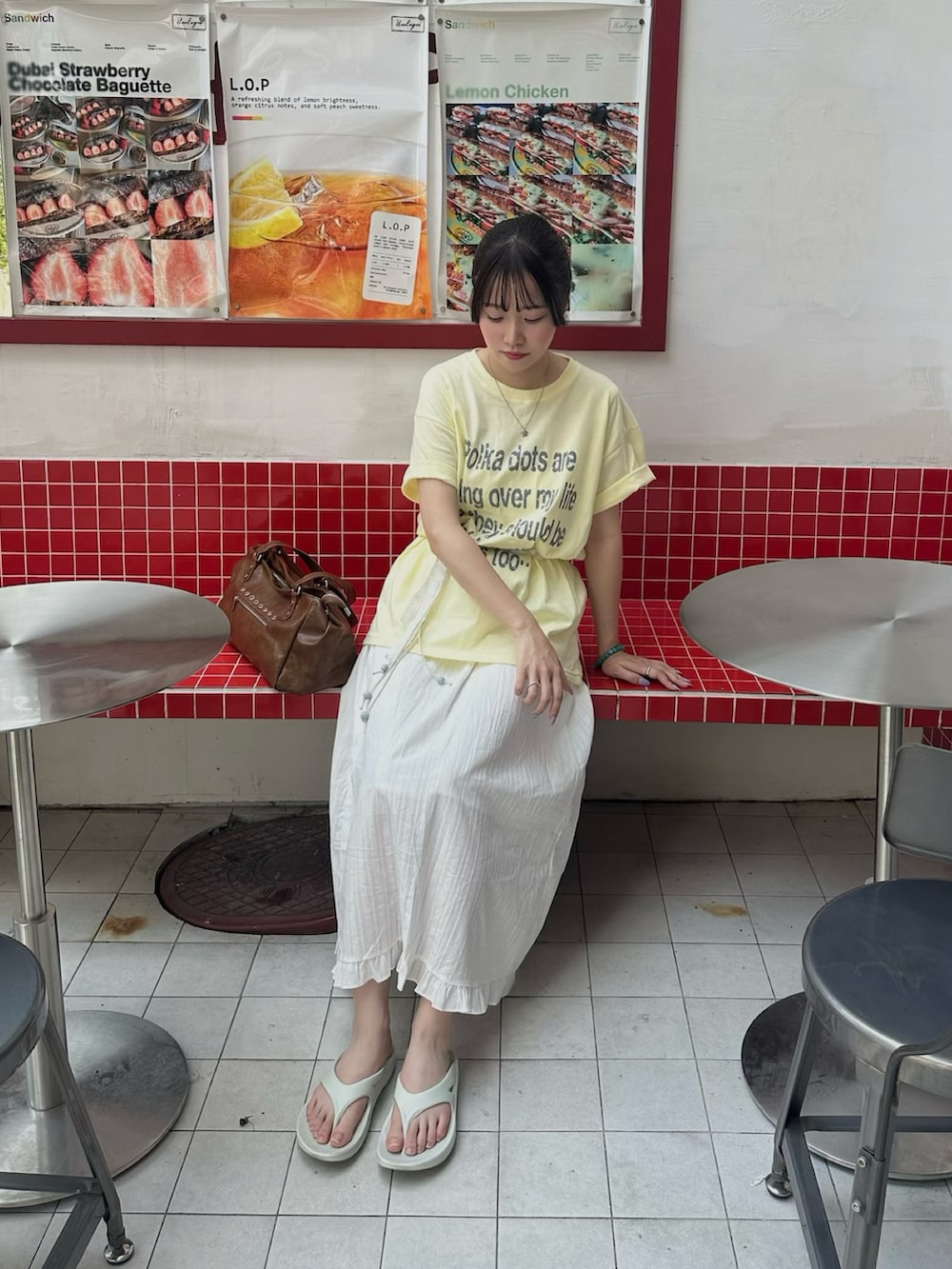 グレー系のサンダル、イエロー系のTシャツ/カットソー、ホワイト系のスカートを着用したレディースの夏コーディネートの2枚目の写真