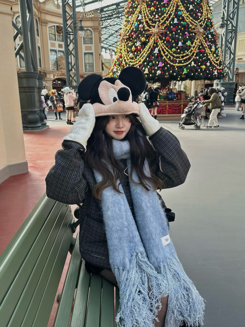 グレー系のテーラードジャケット、ブラック系のブーツ、ブルー系のマフラーを着用したレディースの冬コーディネートの2枚目の写真