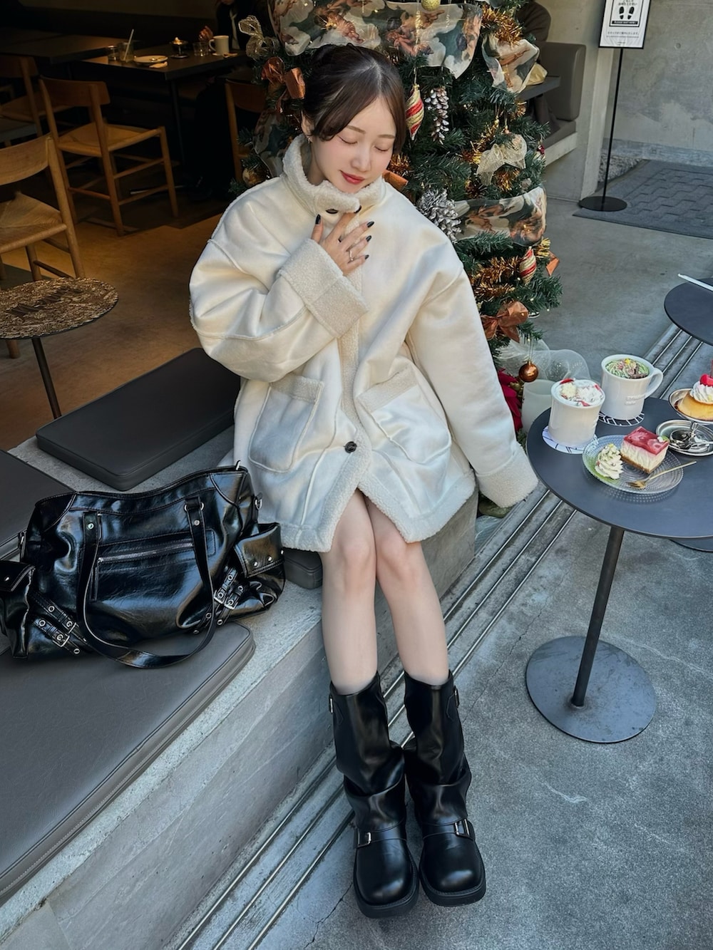 ホワイト系のムートンコート、ブラック系のブーツを着用したレディースの冬コーディネートの2枚目の写真