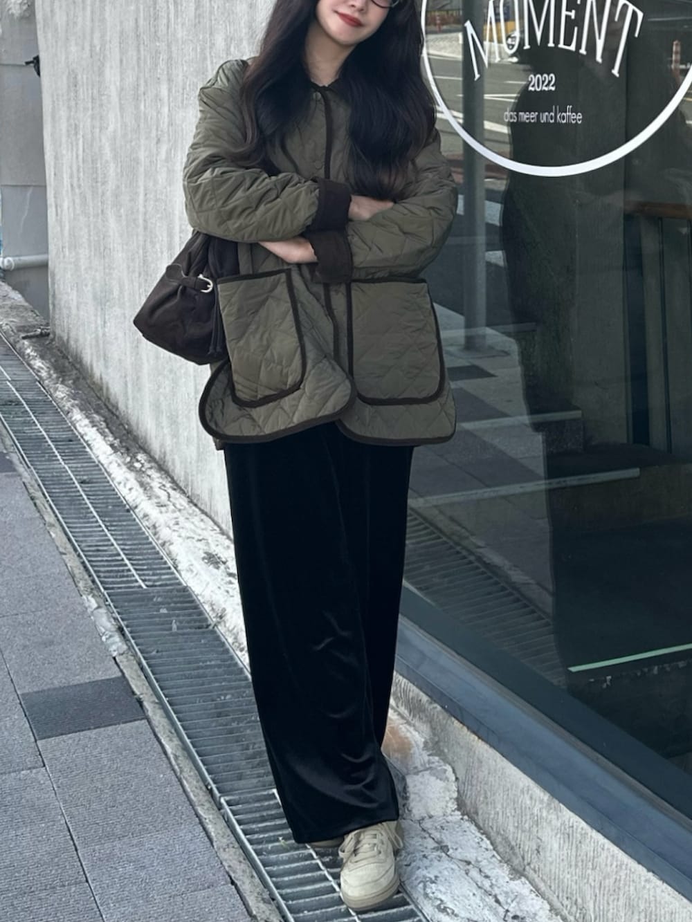 グリーン系のミリタリージャケット、ブラック系のチノパンツ、ブラウン系のボストンバッグを着用したレディースの秋コーディネートの2枚目の写真