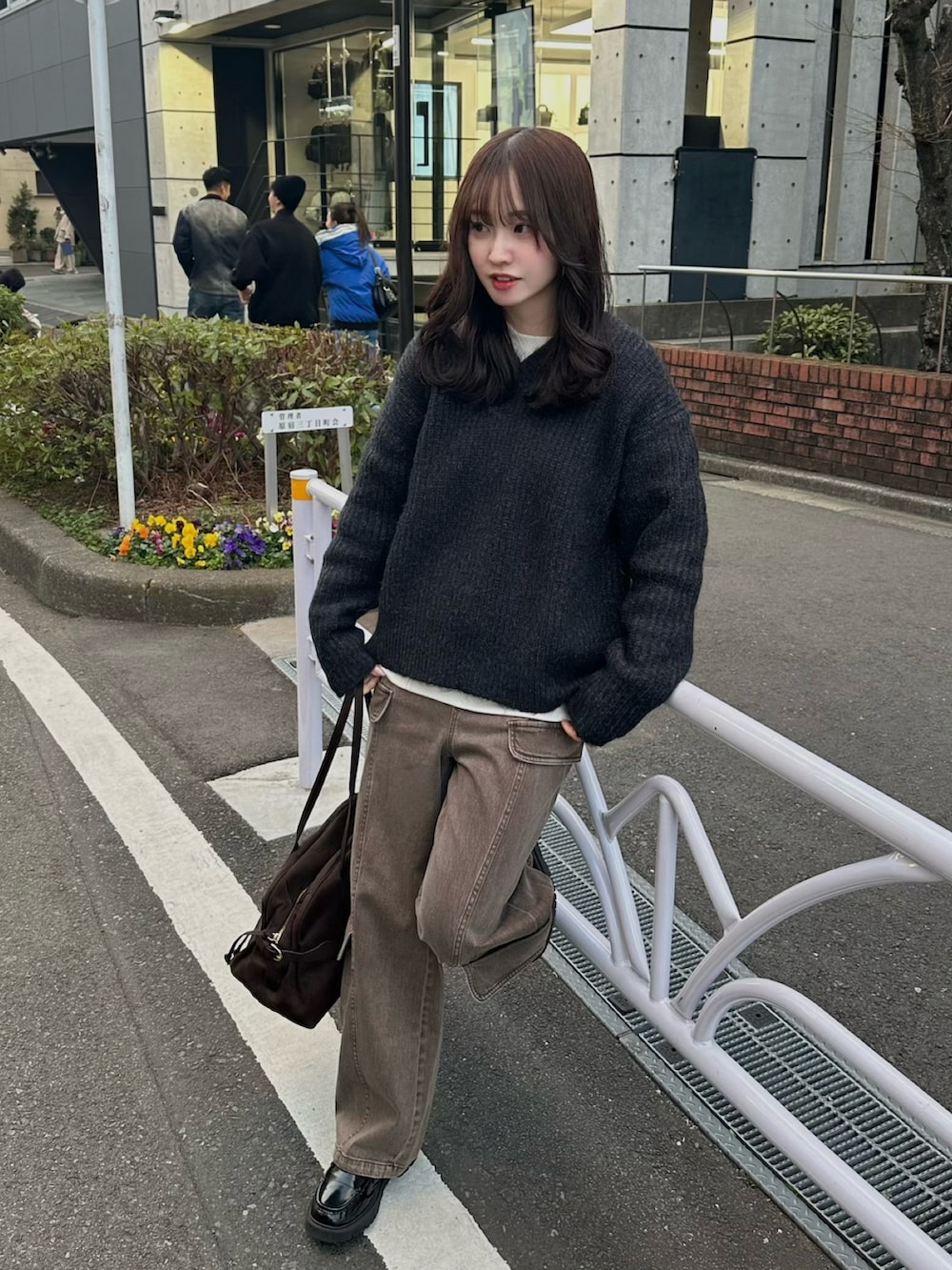 ブラウン系のカーゴパンツ、グレー系のニット/セーター、ブラウン系のボストンバッグを着用したレディースの冬コーディネートの2枚目の写真