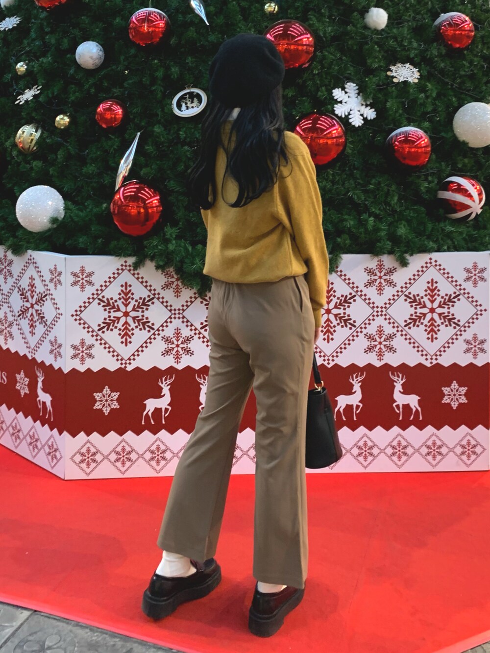 ブラウン系のパンツ、イエロー系のニット/セーター、ホワイト系のトップスを着用したレディースの冬コーディネートの2枚目の写真