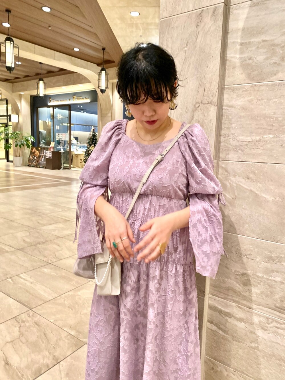 パープル系のワンピース、ブラック系のショルダーバッグを着用したレディースの冬コーディネートの2枚目の写真