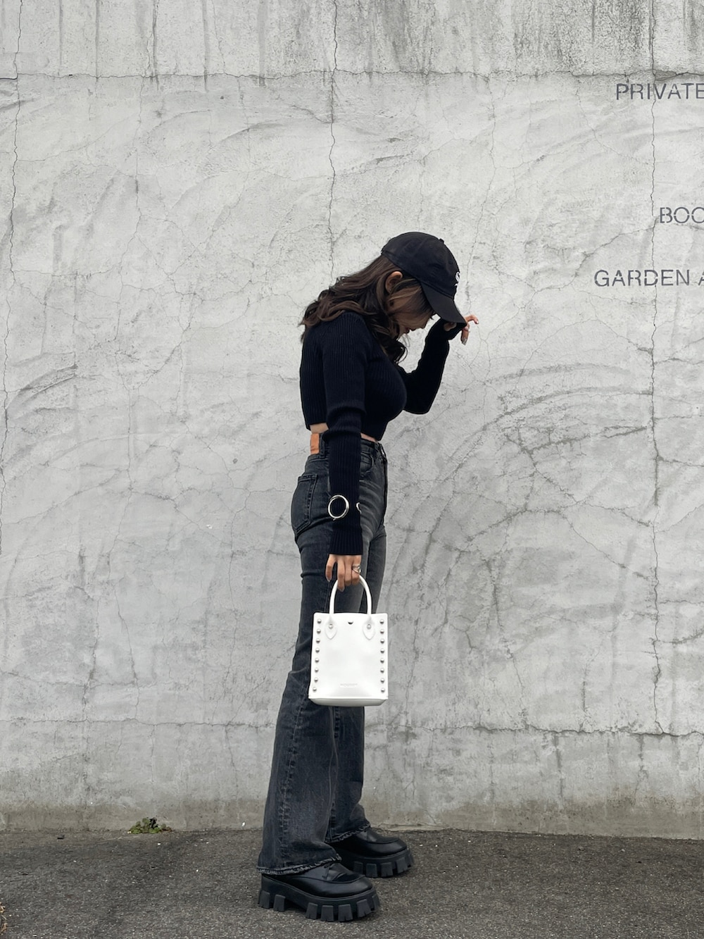 ホワイト系のショルダーバッグ、ブラック系のデニムパンツ、ブラック系のニット/セーターを着用したレディースの冬コーディネートの2枚目の写真