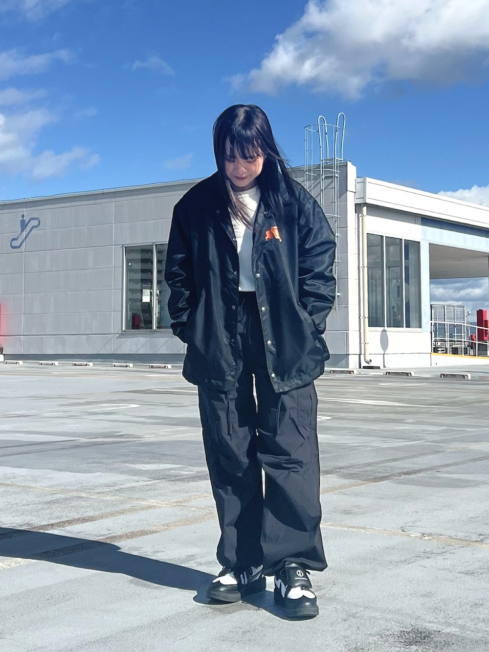 オレンジ系のナイロンジャケット、ブラック系のカーゴパンツ、ホワイト系のTシャツ/カットソーを着用したレディースの冬コーディネートの2枚目の写真