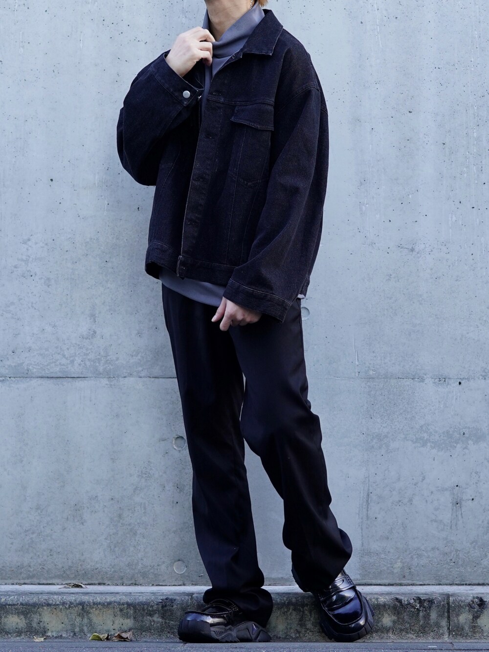 ブラック系のデニムジャケット、ブラック系のスラックス、グレー系のTシャツ/カットソーを着用したメンズの冬コーディネートの3枚目の写真