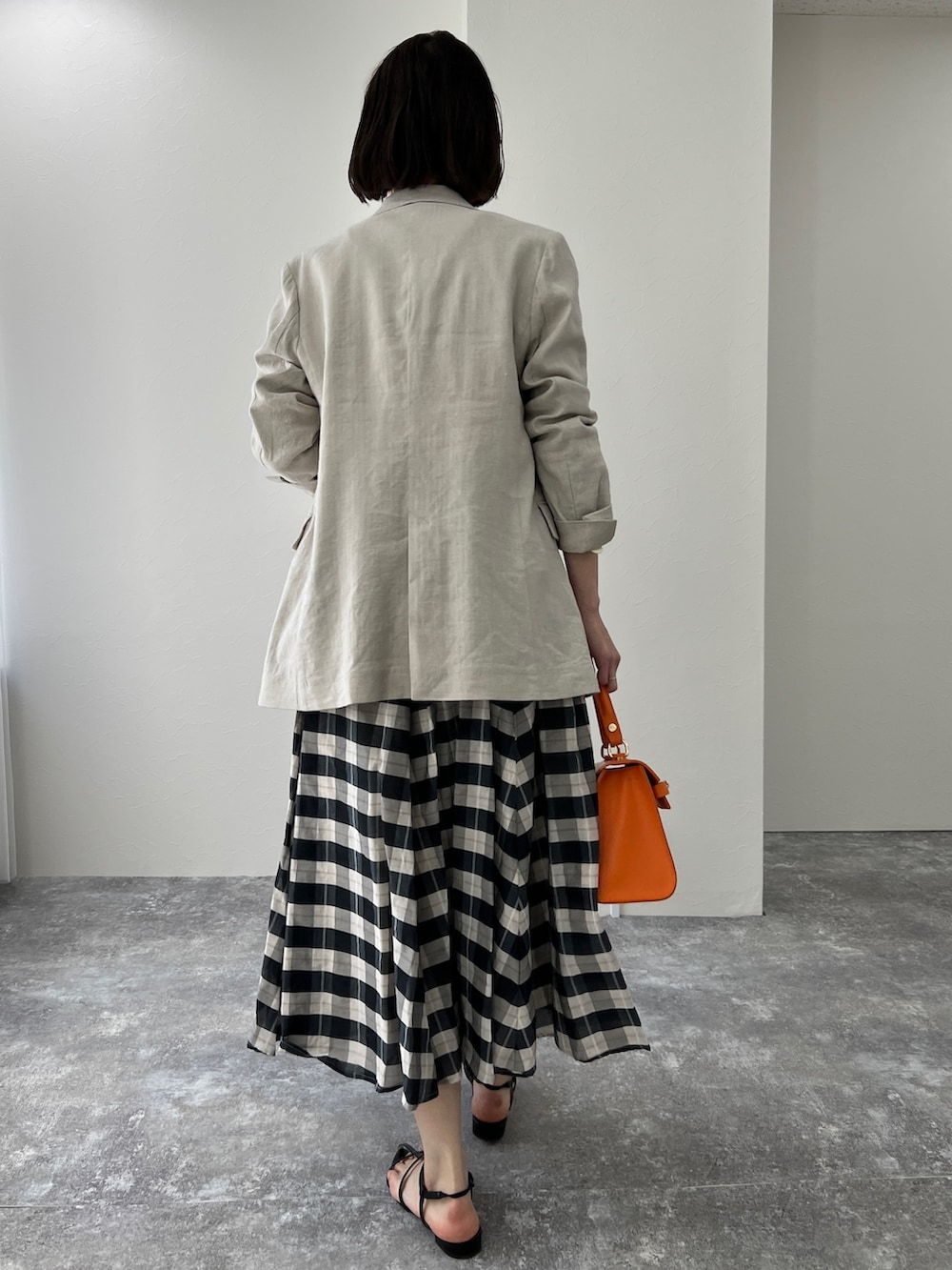 ベージュ系のテーラードジャケット、ブラック系のサンダル、オレンジ系のショルダーバッグを着用したレディースの冬コーディネートの3枚目の写真