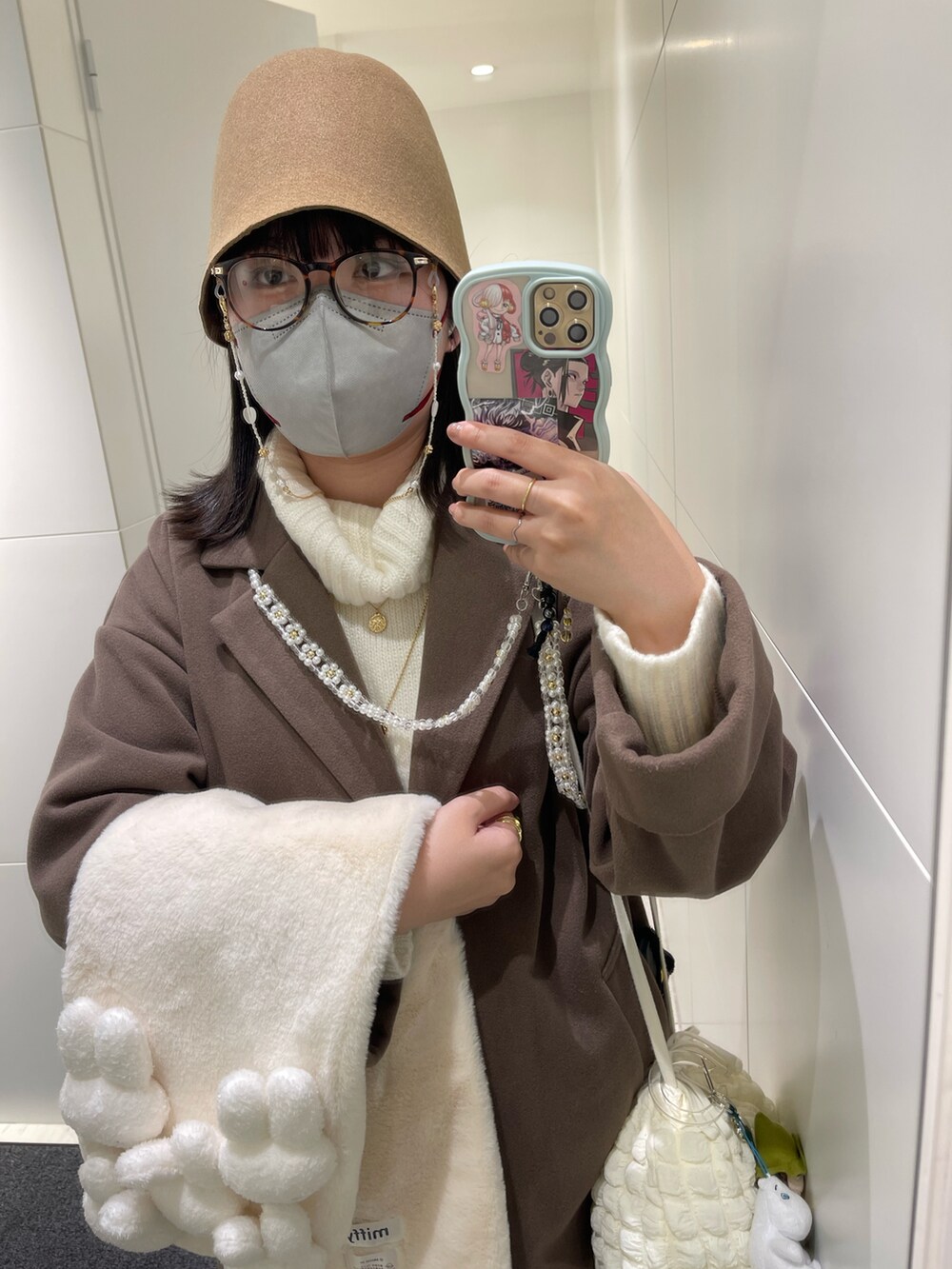 ブラウン系のステンカラーコート、ブラック系のブーツ、ホワイト系のショルダーバッグを着用したレディースの冬コーディネートの2枚目の写真