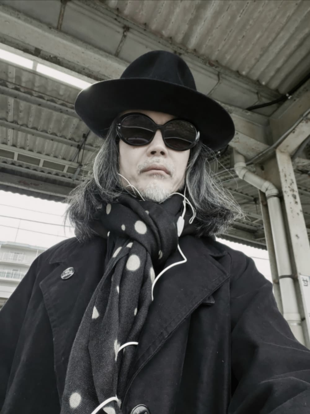 ブラック系のチェスターコート、ブラック系のデニムパンツ、ブラック系のドレスシューズを着用したメンズの冬コーディネートの4枚目の写真