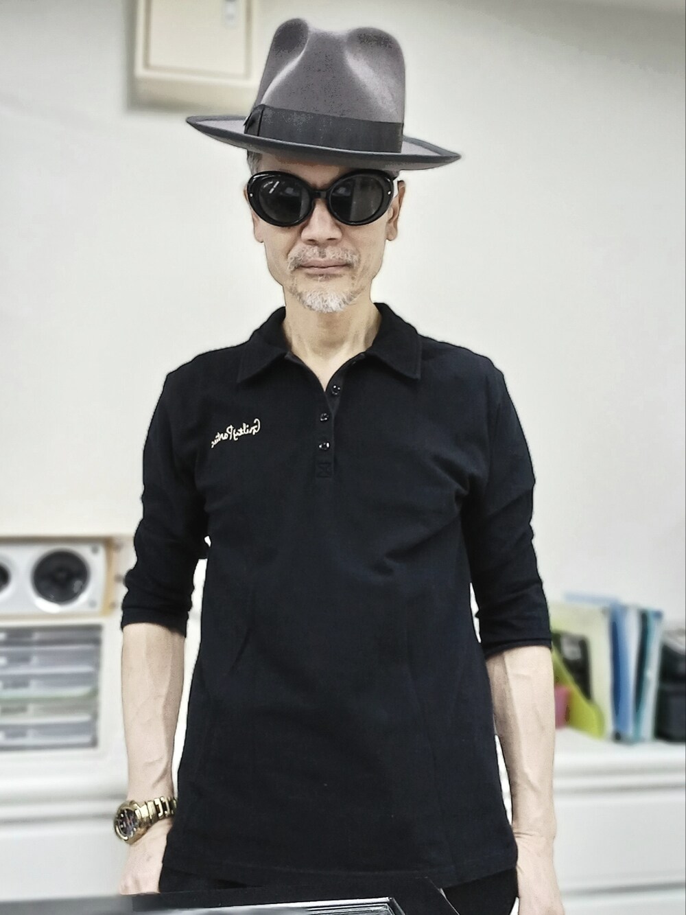 ブラック系のスニーカー、ブラック系のチノパンツ、ブラック系のポロシャツを着用したメンズの春コーディネートの2枚目の写真