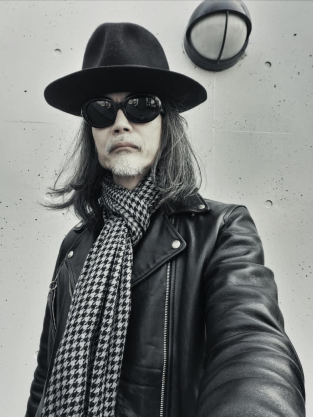 ブラック系のデニムパンツ、ブラック系のスニーカー、ブラック系のライダースジャケットを着用したメンズの春コーディネートの2枚目の写真