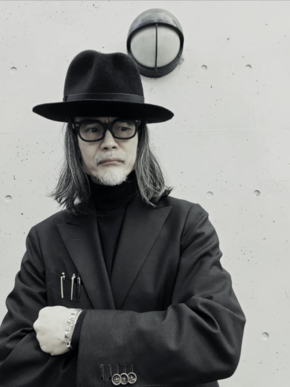 ブラウン系のテーラードジャケット、ブラック系のブーツ、ブラック系のニット/セーターを着用したメンズの冬コーディネートの3枚目の写真