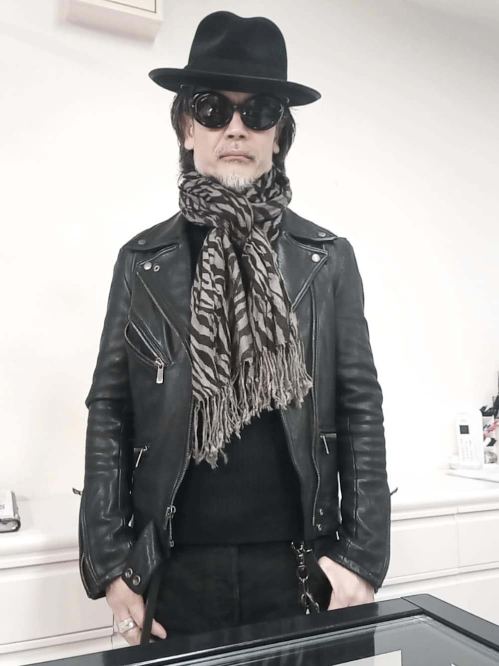 ブラック系のデニムパンツ、ブラック系のライダースジャケット、ブラック系のドレスシューズを着用したメンズの冬コーディネートの2枚目の写真