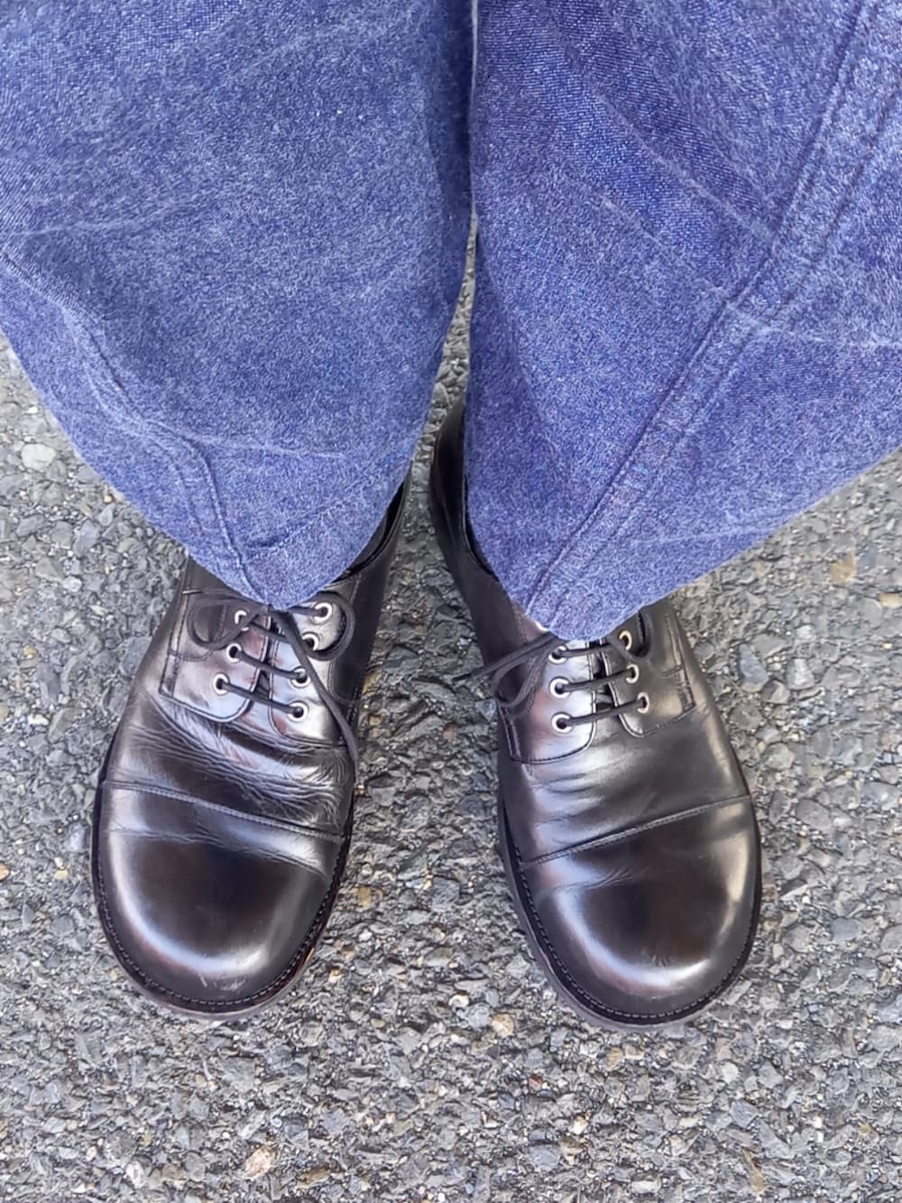 ブラック系のライダースジャケット、ブルー系のデニムパンツ、ブラック系のドレスシューズを着用したメンズの春コーディネートの5枚目の写真