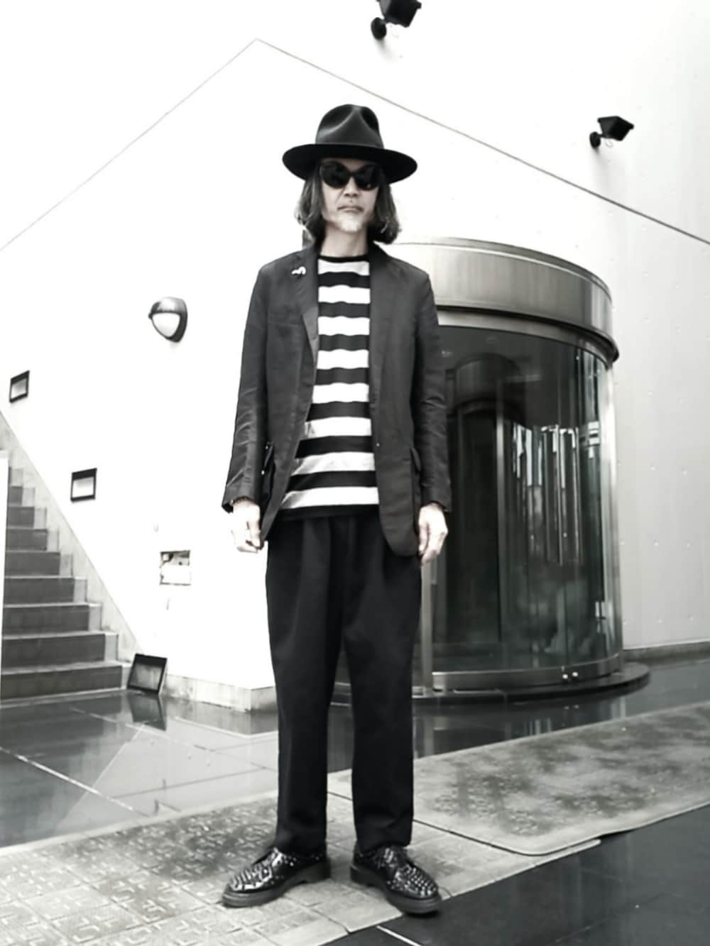 ブラック系のテーラードジャケット、ブラック系のスラックス、ブラック系のドレスシューズを着用したメンズの春コーディネートの3枚目の写真