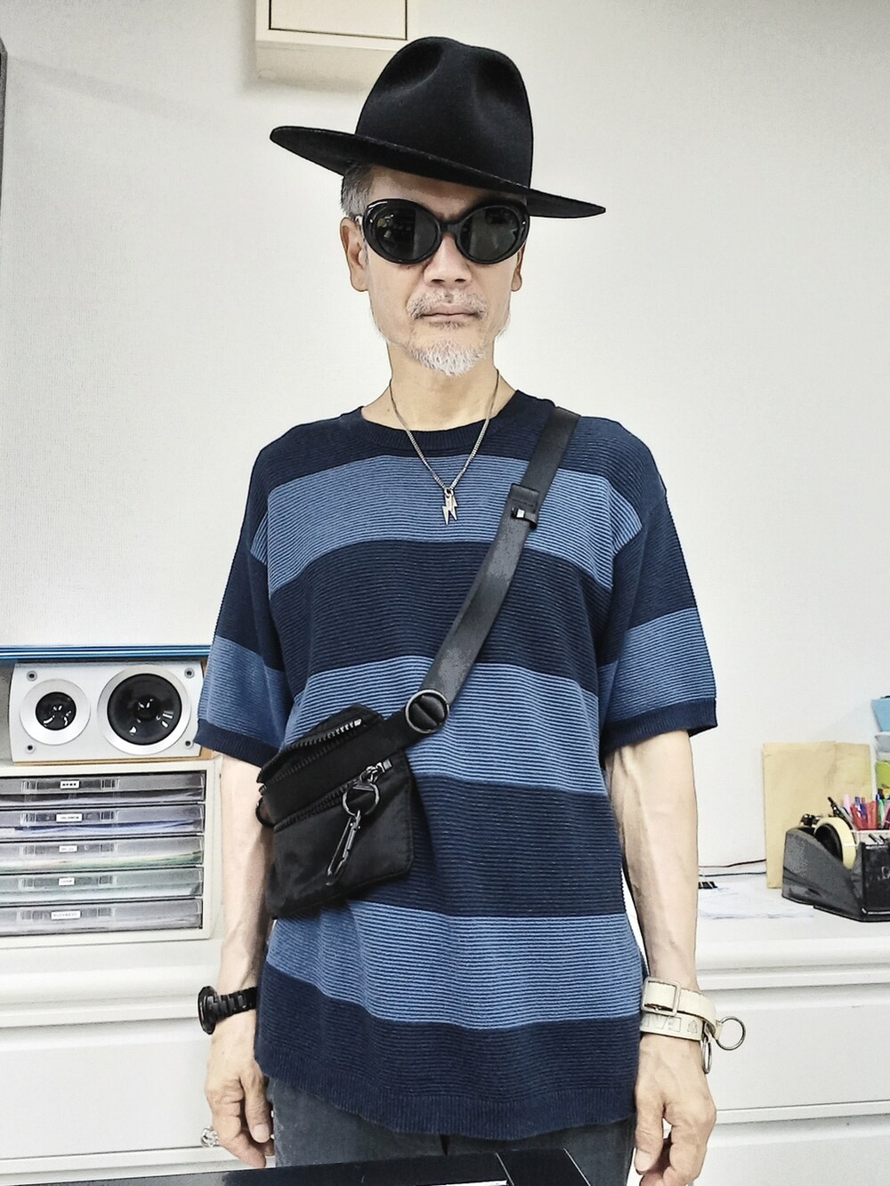 グレー系のその他パンツ、ブラック系のドレスシューズ、ブルー系のニット/セーターを着用したメンズの夏コーディネートの2枚目の写真