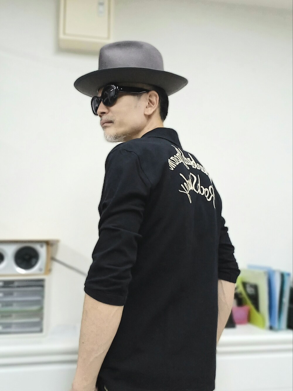 ブラック系のスニーカー、ブラック系のチノパンツ、ブラック系のポロシャツを着用したメンズの春コーディネートの3枚目の写真