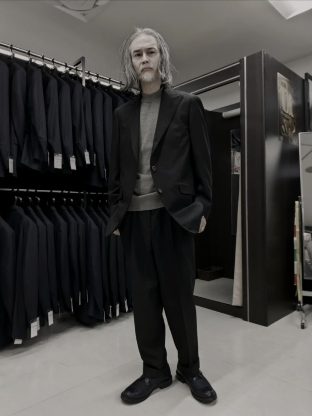 ブラウン系のテーラードジャケット、ブラック系のブーツ、ブラック系のニット/セーターを着用したメンズの冬コーディネートの4枚目の写真