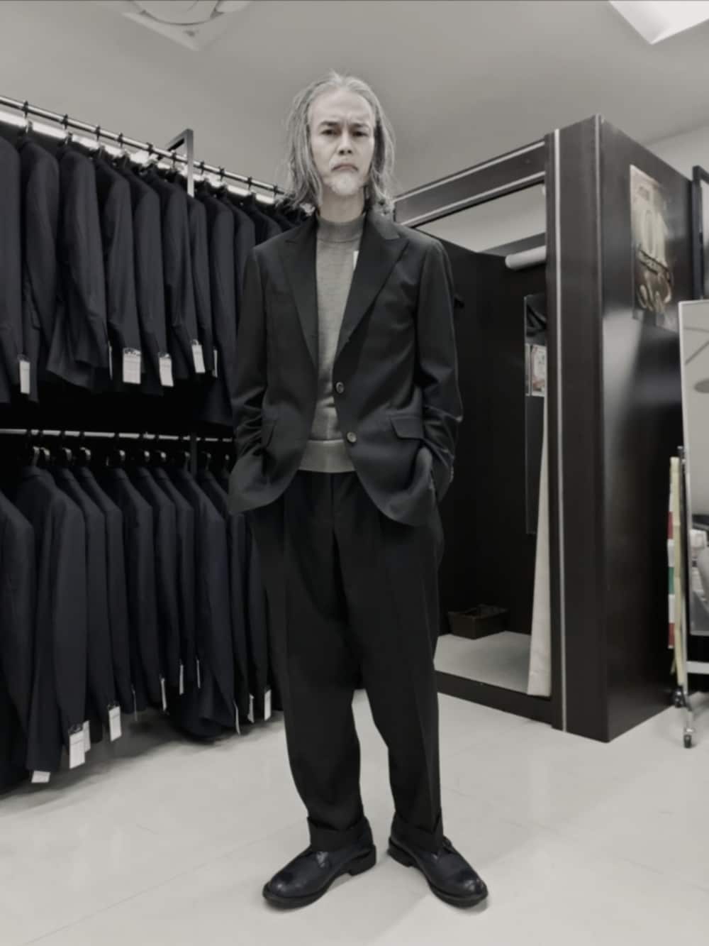 ブラウン系のテーラードジャケット、ブラック系のブーツ、ブラック系のニット/セーターを着用したメンズの冬コーディネートの5枚目の写真