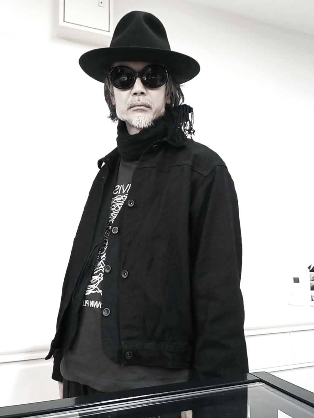 ブラック系のデニムジャケット、ブラック系のベスト、グレー系のTシャツ/カットソーを着用したメンズの春コーディネートの2枚目の写真