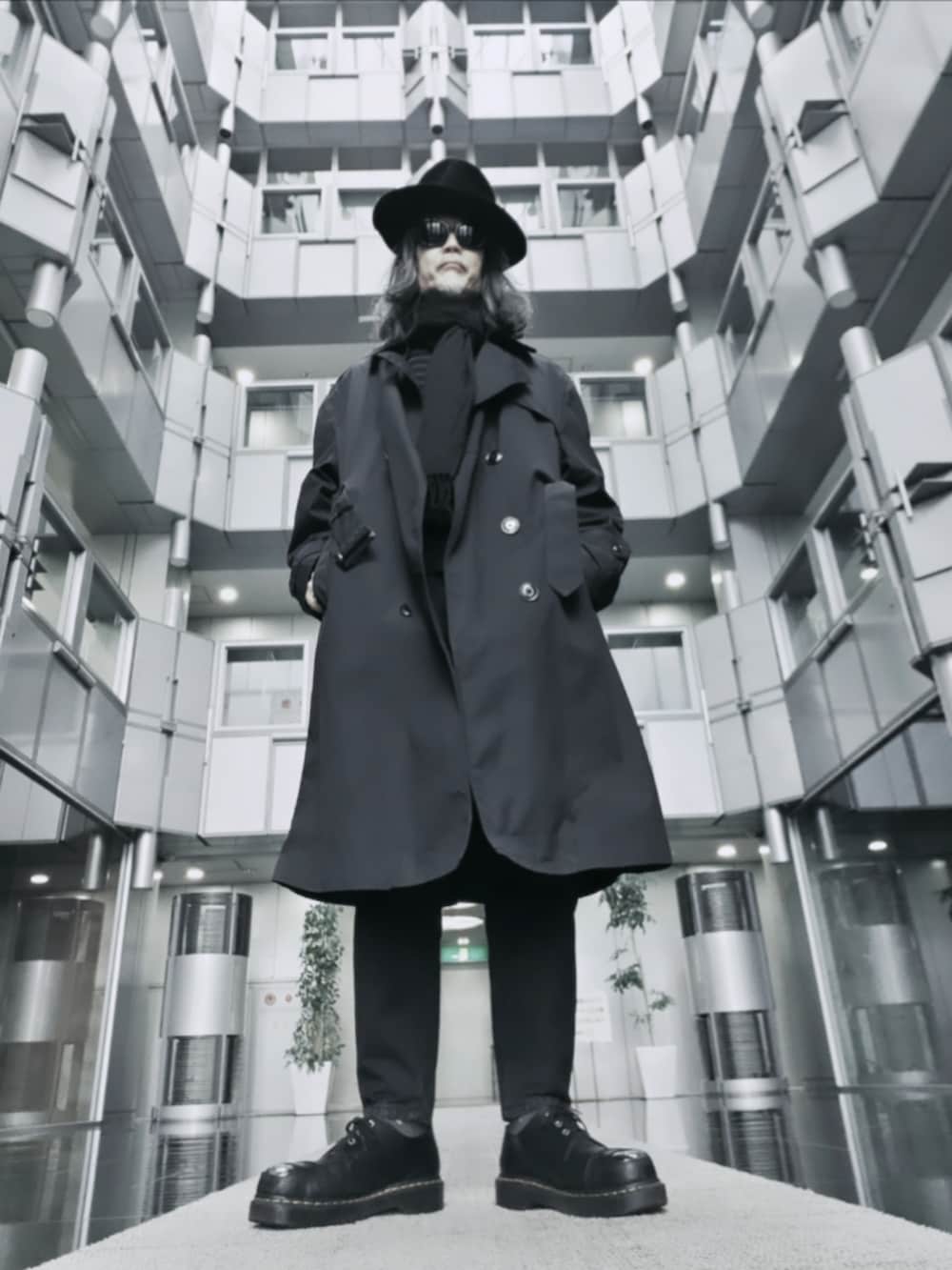 ブラック系のデニムパンツ、ブラック系のドレスシューズ、ブラック系のニット/セーターを着用したメンズの春コーディネートの2枚目の写真