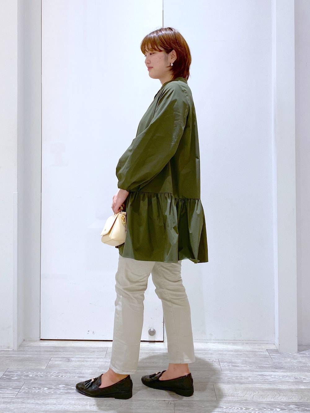 グリーン系のシャツ/ブラウス、ベージュ系のバッグ、グレー系のデニムパンツを着用したレディースの秋コーディネートの3枚目の写真