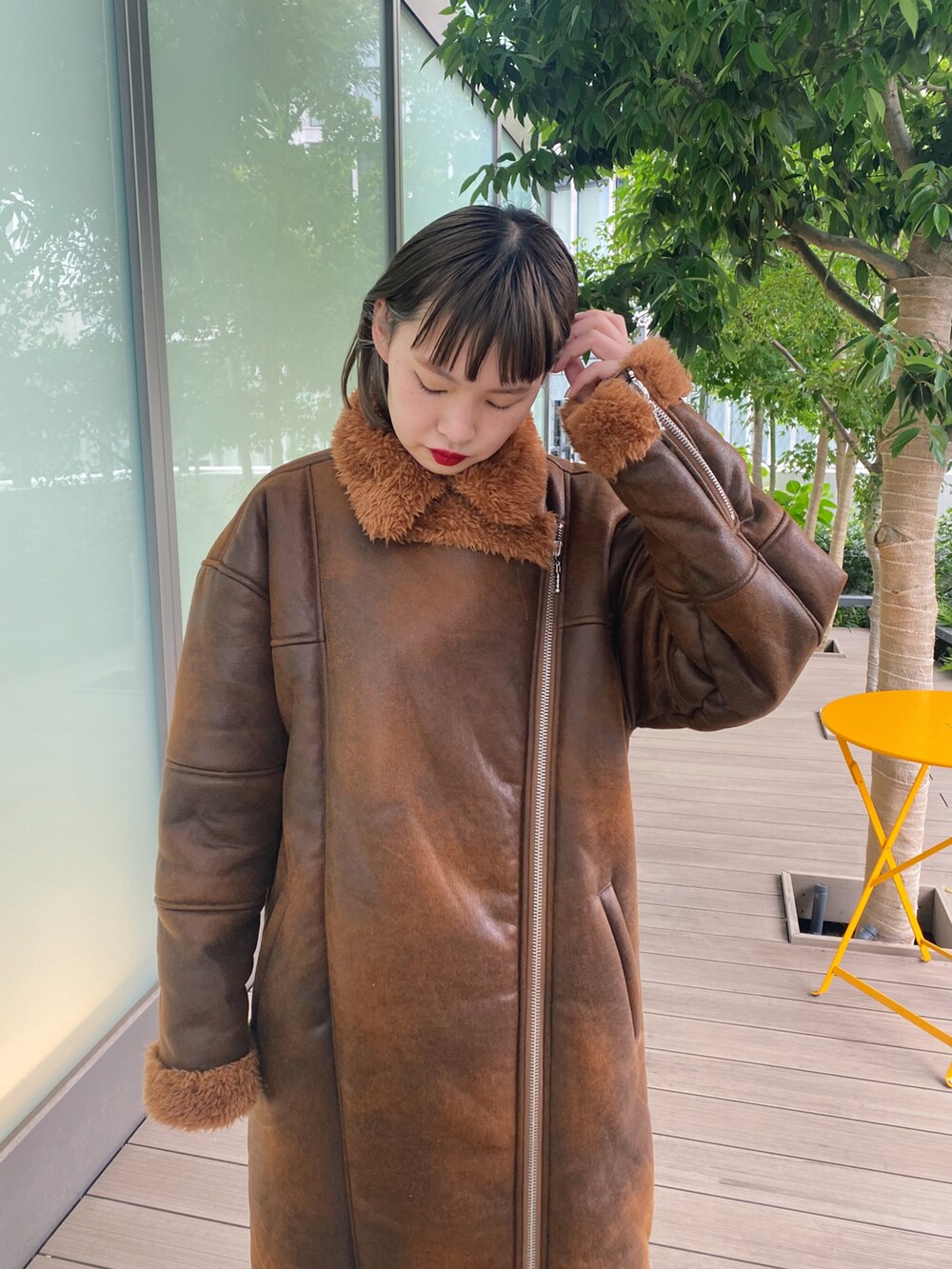 ブラウン系のムートンコート、ホワイト系のブーツを着用したレディースの秋コーディネートの2枚目の写真