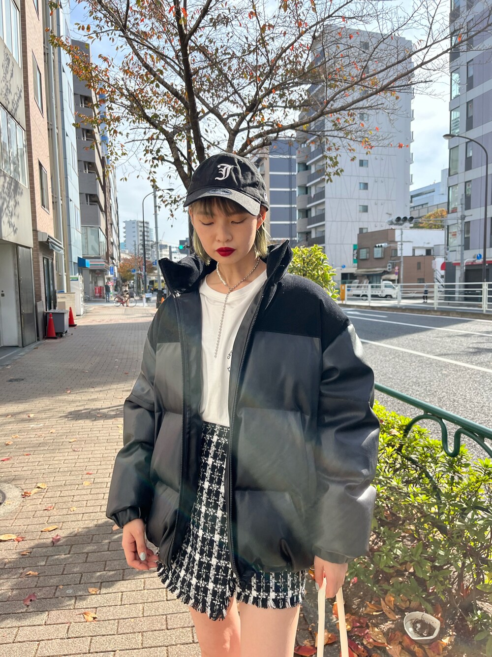 ホワイト系のTシャツ/カットソー、ブラック系のスカート、ブラック系のダウンジャケット/コートを着用したレディースの冬コーディネートの2枚目の写真