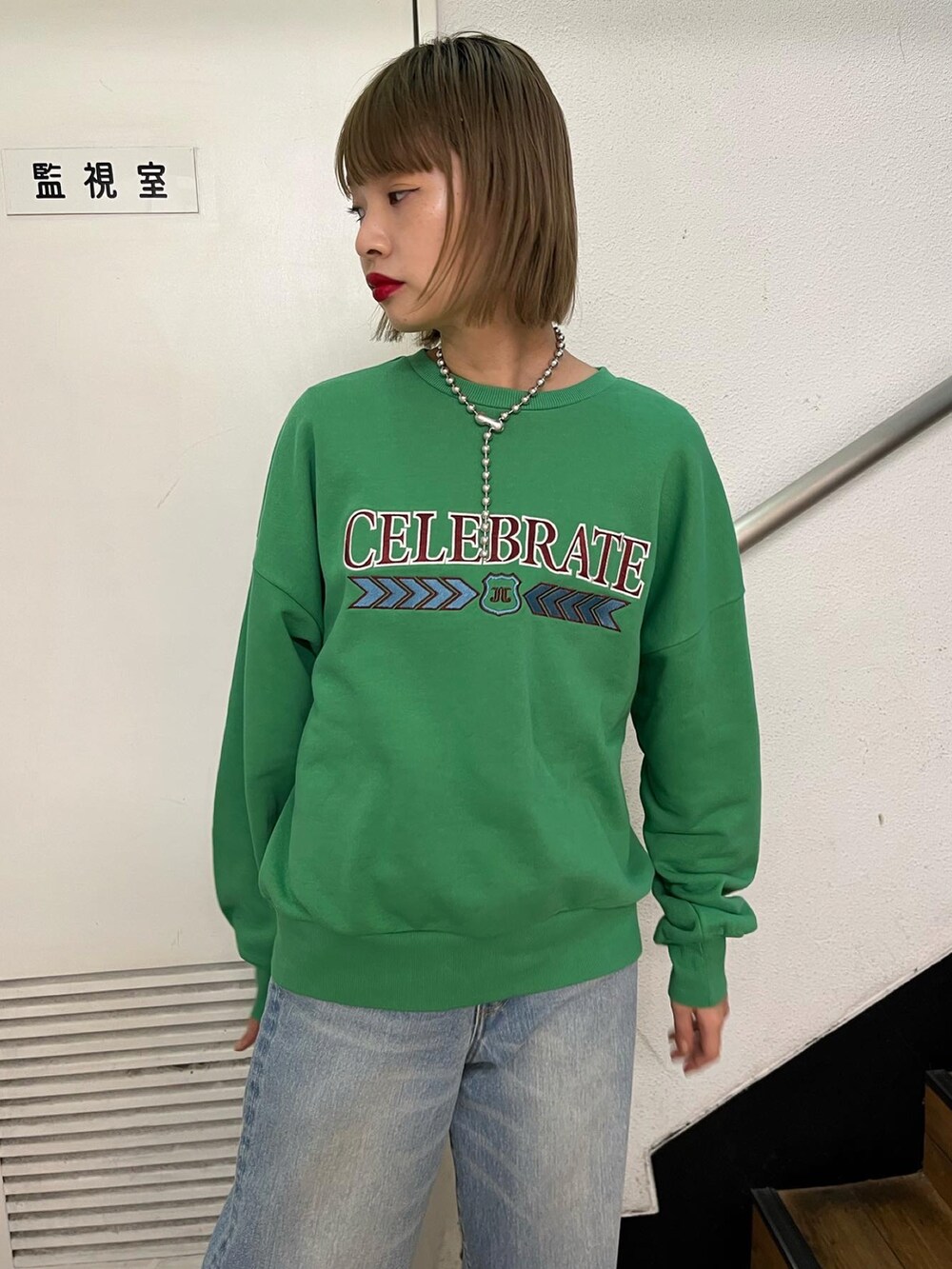 ブルー系のデニムパンツ、グリーン系のスウェット、ブラック系のスニーカーを着用したレディースの冬コーディネートの2枚目の写真