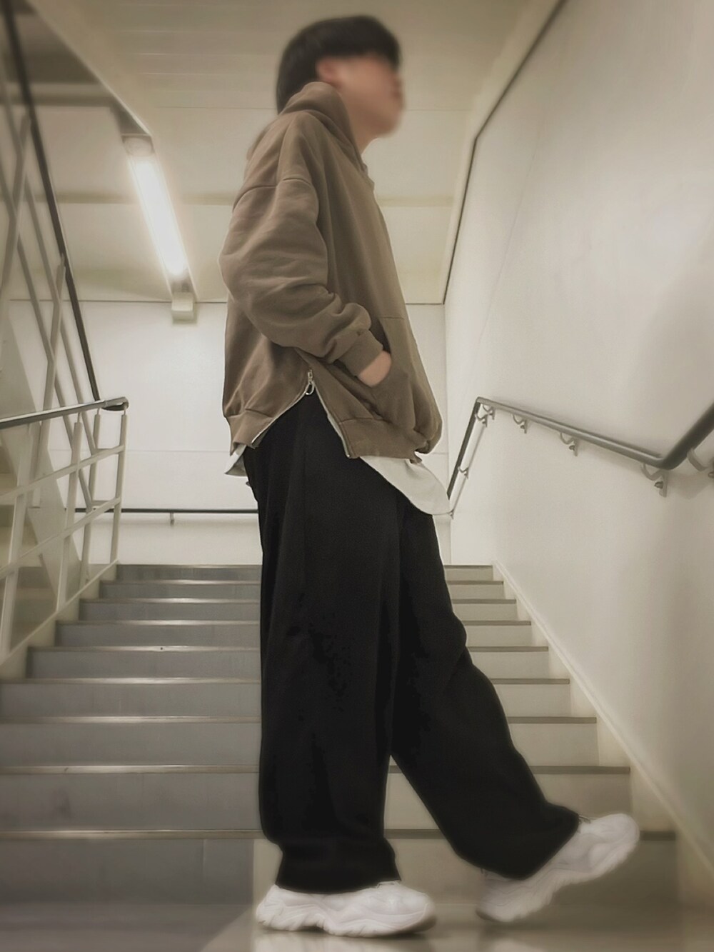 ブラウン系のパーカー、ホワイト系のTシャツ/カットソー、ブラック系のスラックスを着用したメンズの冬コーディネートの2枚目の写真