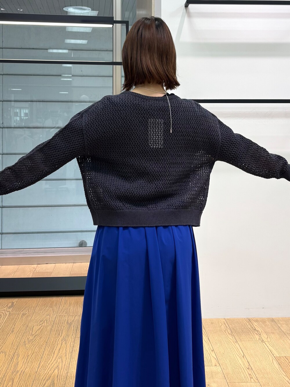 グレー系のカーディガン/ボレロ、ホワイト系のトートバッグ、ブルー系のスカートを着用したレディースの春コーディネートの7枚目の写真