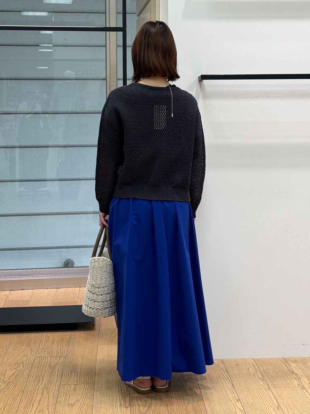グレー系のカーディガン/ボレロ、ホワイト系のトートバッグ、ブルー系のスカートを着用したレディースの春コーディネートの4枚目の写真