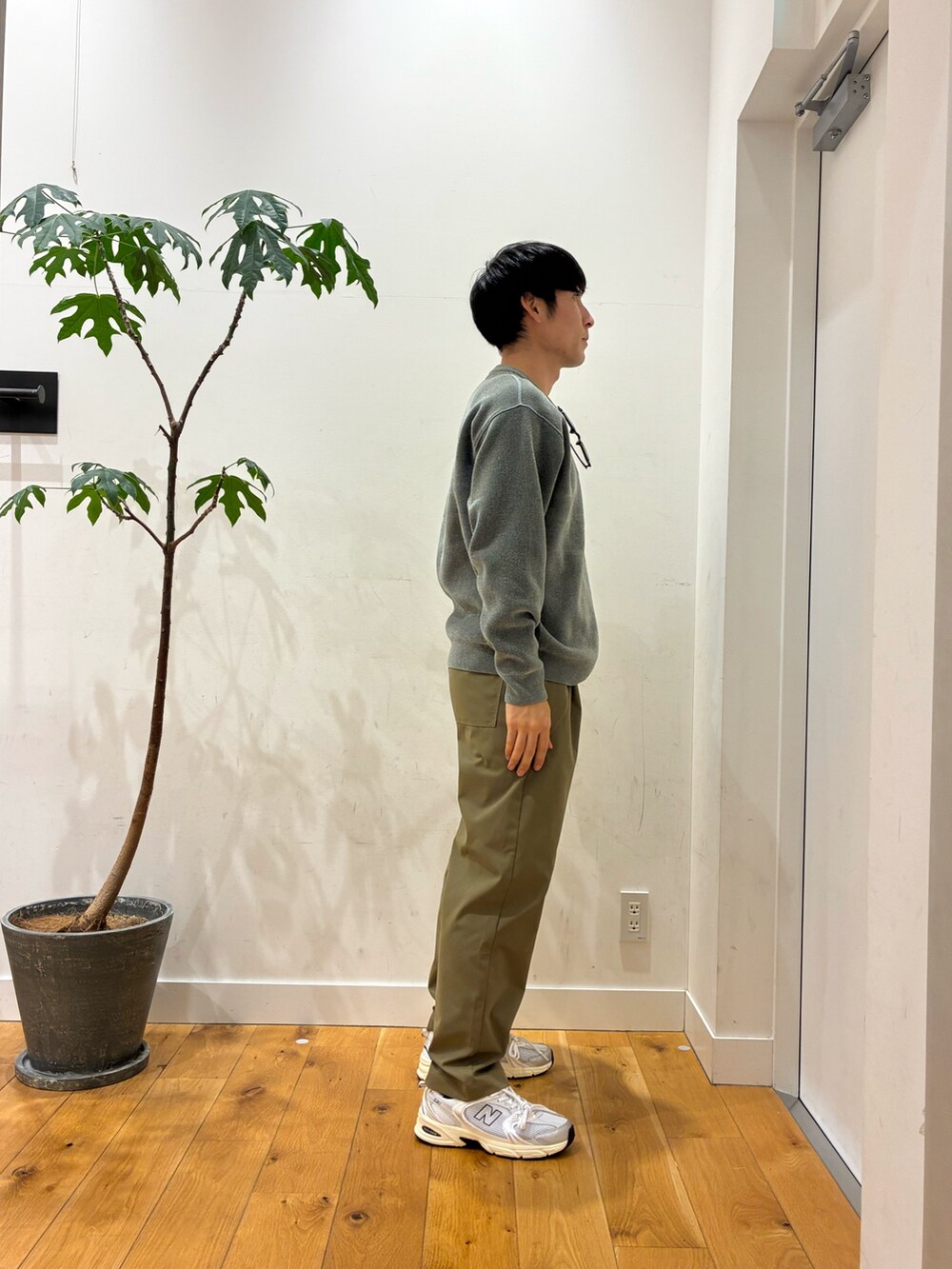 ベージュ系のその他パンツ、シルバー系のスニーカー、グリーン系のニット/セーターを着用したメンズの秋コーディネートの3枚目の写真