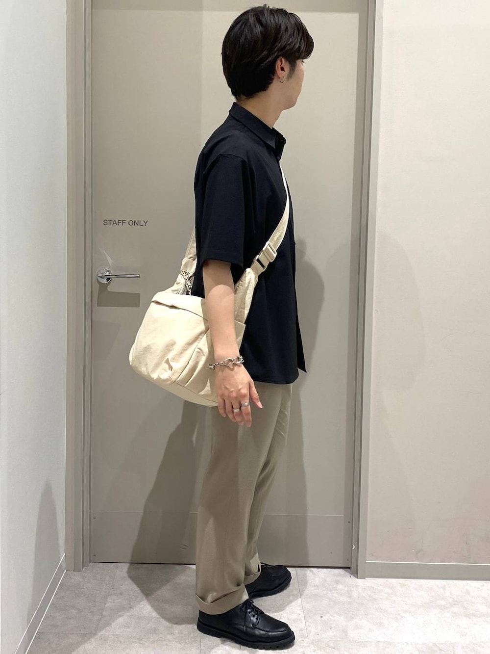 ホワイト系のショルダーバッグ、グレー系のその他シューズ、ベージュ系のスラックスを着用したメンズの夏コーディネートの2枚目の写真