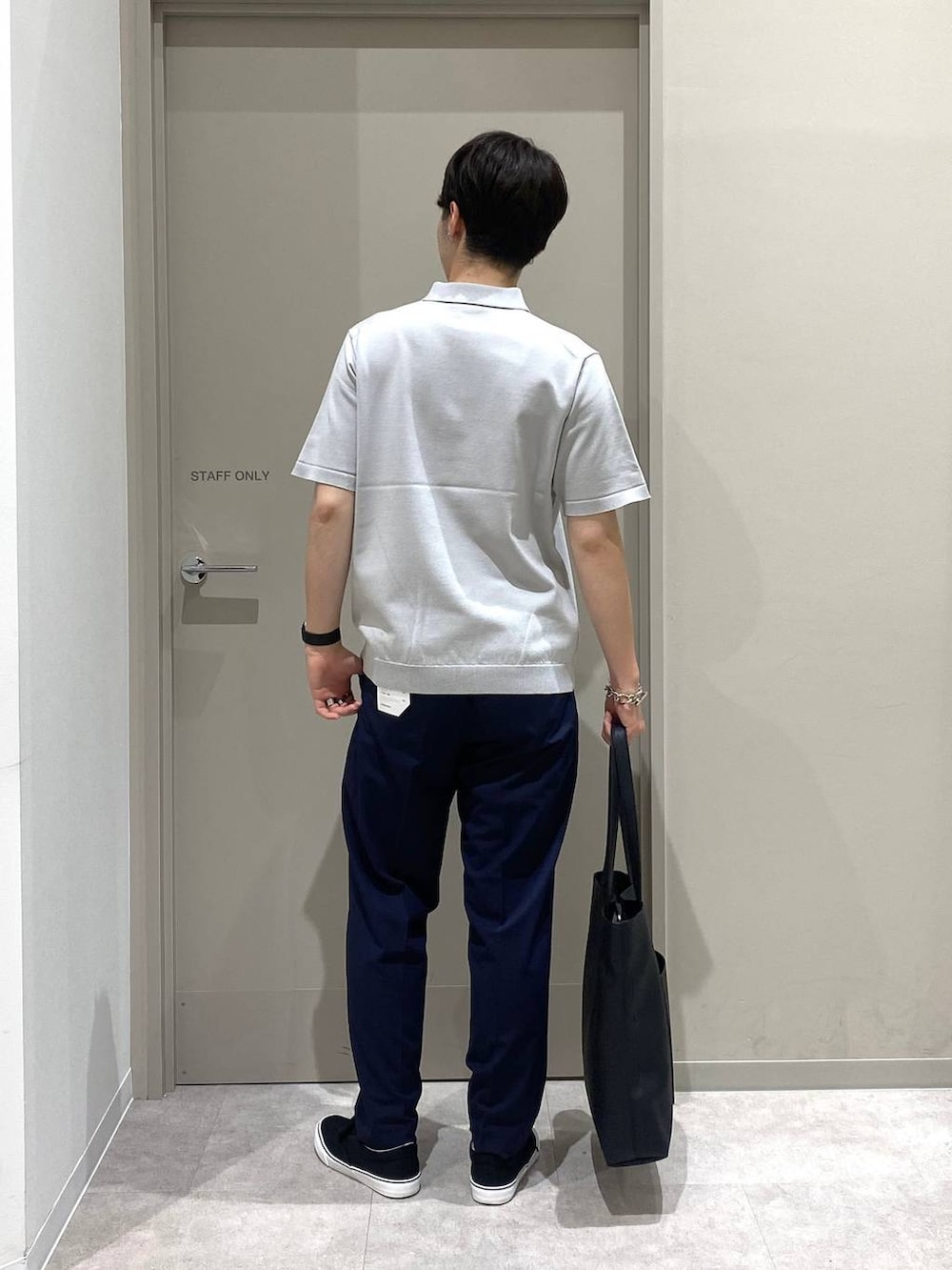 ブラック系のトートバッグ、ブルー系のスラックス、ブラック系のスニーカーを着用したメンズの夏コーディネートの3枚目の写真