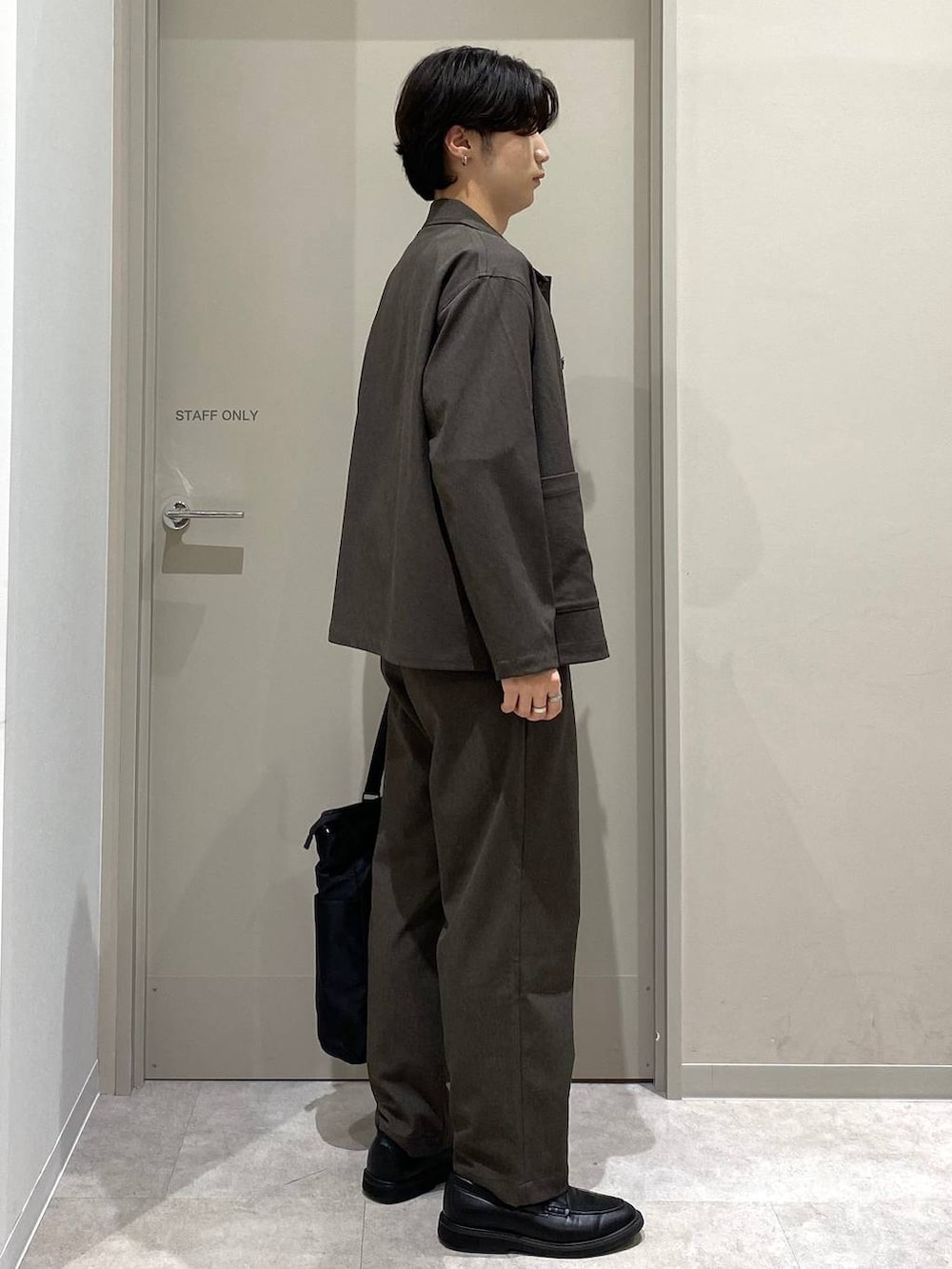 ブラック系のトートバッグ、ブラウン系のその他パンツ、グレー系のその他シューズを着用したメンズの秋コーディネートの3枚目の写真