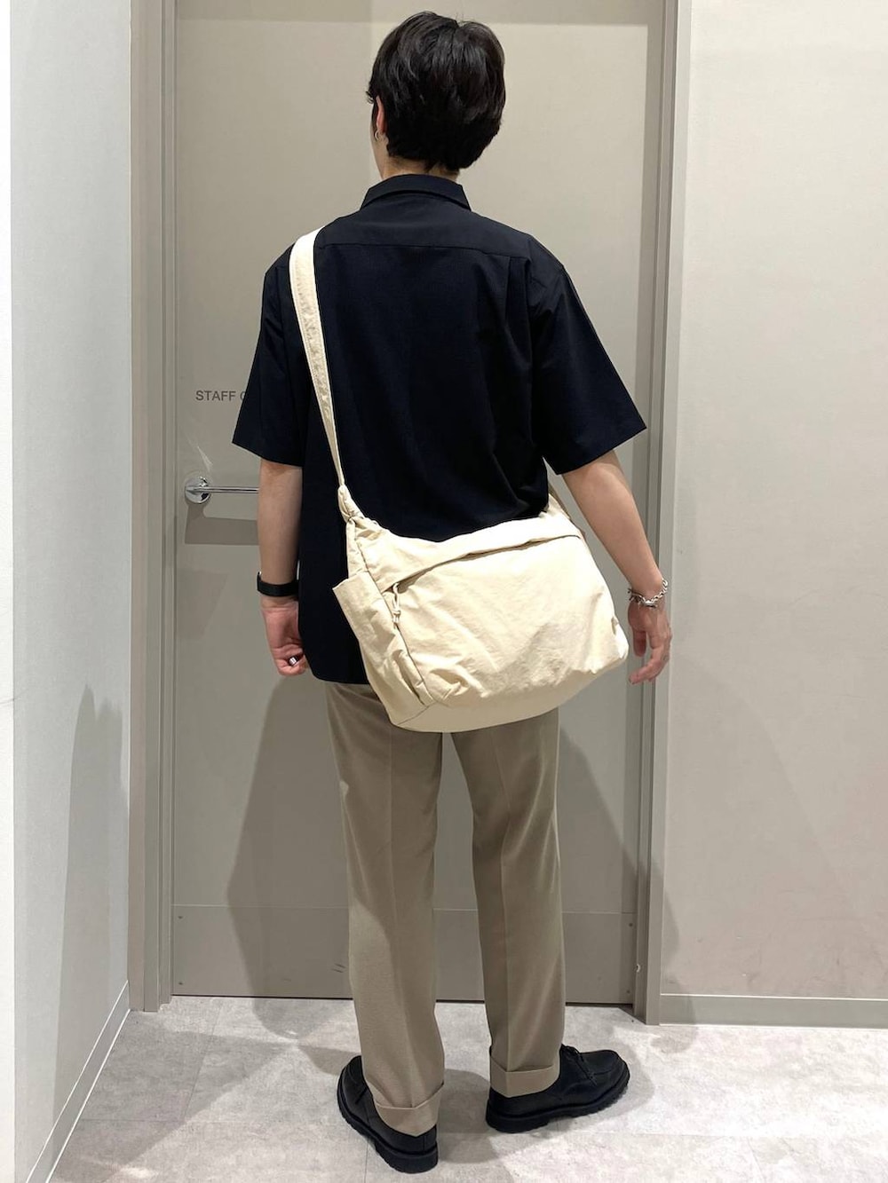 ホワイト系のショルダーバッグ、グレー系のその他シューズ、ベージュ系のスラックスを着用したメンズの夏コーディネートの3枚目の写真