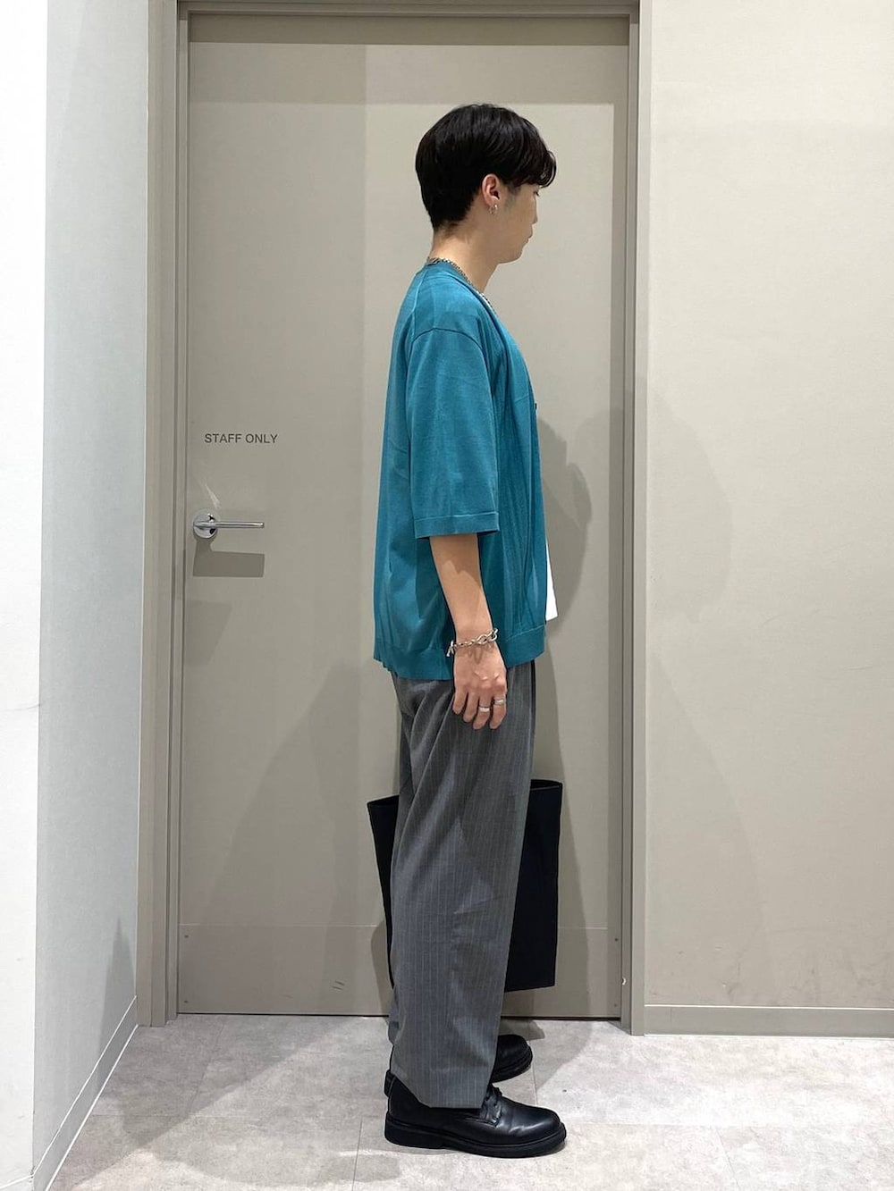 ブラック系のトートバッグ、グレー系のスラックス、ホワイト系のTシャツ/カットソーを着用したメンズの夏コーディネートの2枚目の写真