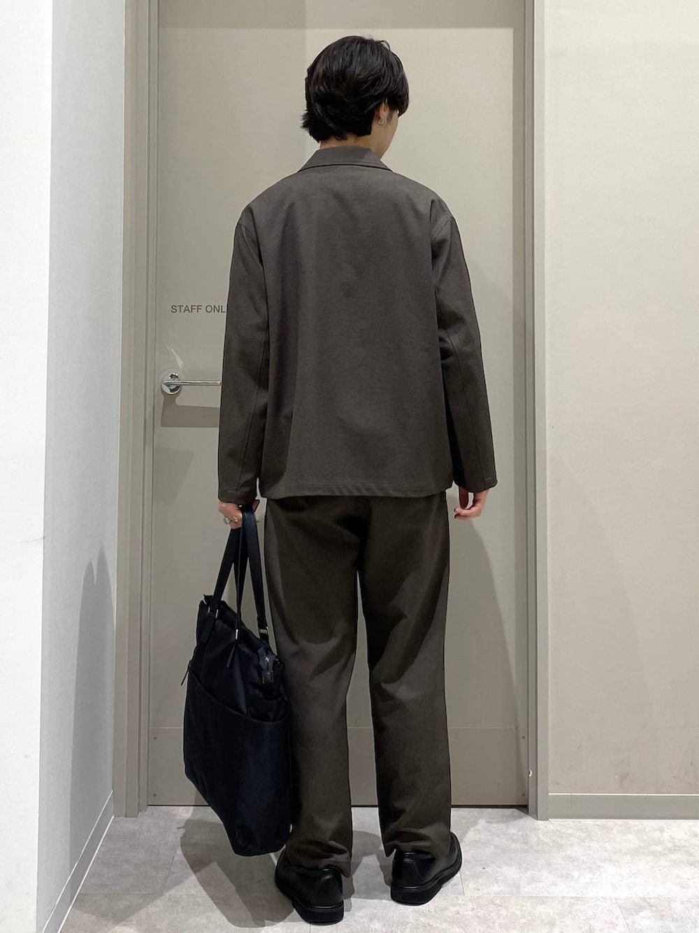 ブラック系のトートバッグ、ブラウン系のその他パンツ、グレー系のその他シューズを着用したメンズの秋コーディネートの4枚目の写真