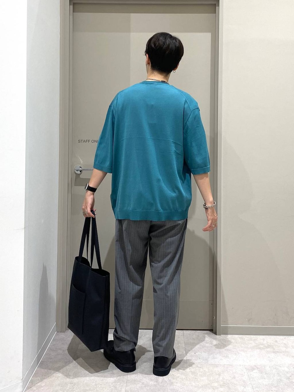 ブラック系のトートバッグ、グレー系のスラックス、ホワイト系のTシャツ/カットソーを着用したメンズの夏コーディネートの3枚目の写真