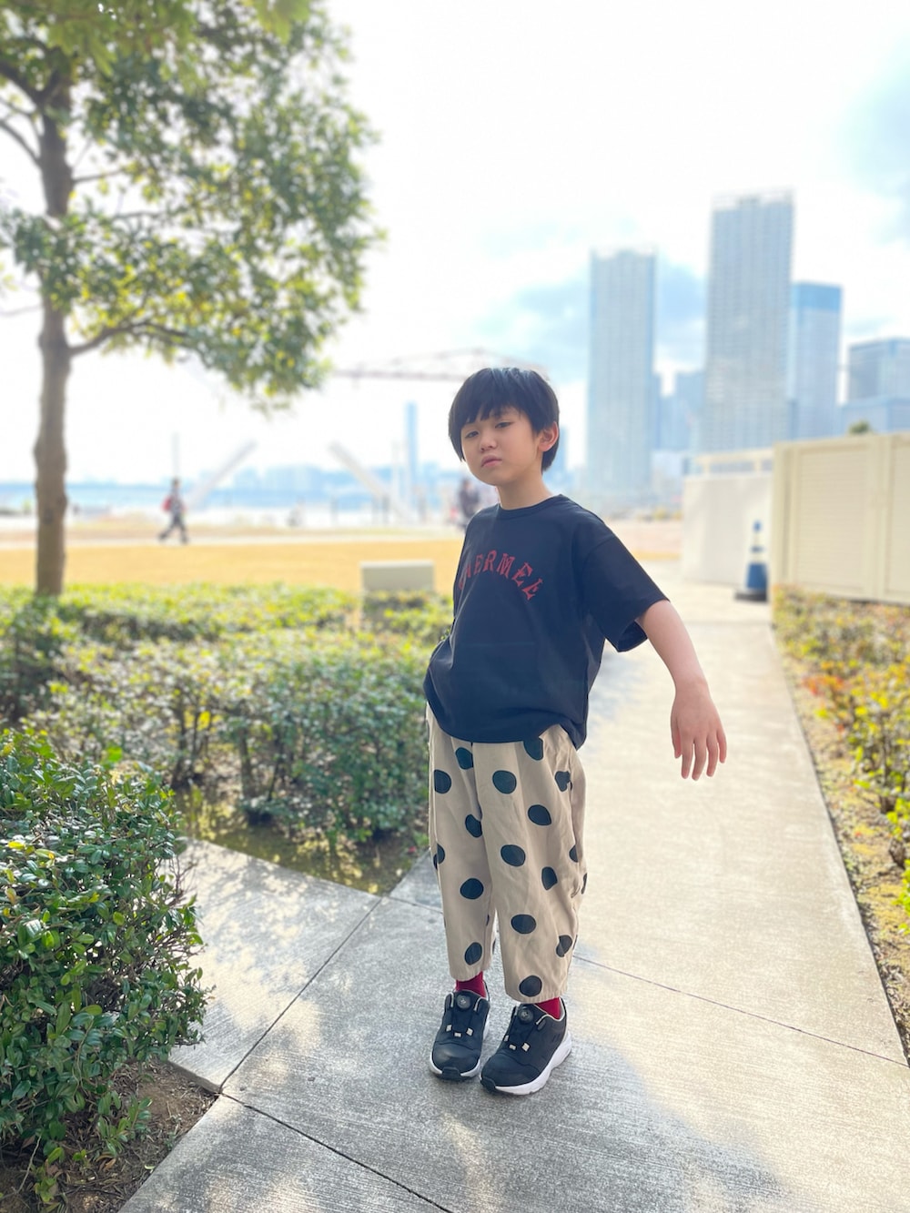 ブラック系のスニーカー、ベージュ系のチノパンツ、ブラック系のTシャツ/カットソーを着用したキッズの春コーディネートの2枚目の写真