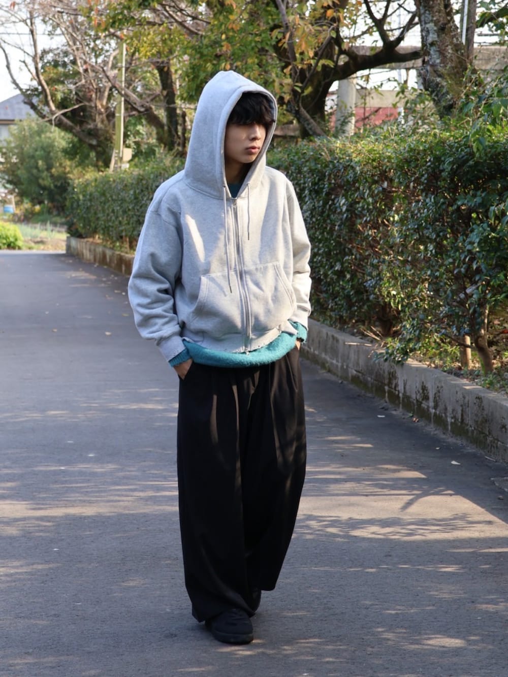 グレー系のパーカー、ブラック系のその他パンツ、ブラック系のスニーカーを着用したメンズの秋コーディネートの2枚目の写真