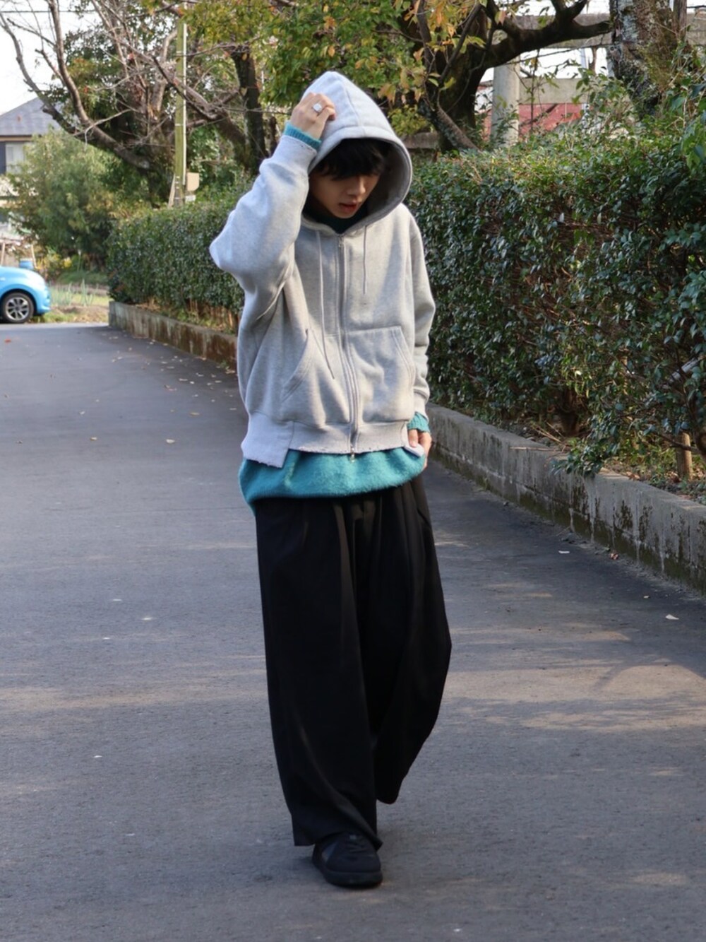 グレー系のパーカー、ブラック系のその他パンツ、ブラック系のスニーカーを着用したメンズの秋コーディネートの3枚目の写真