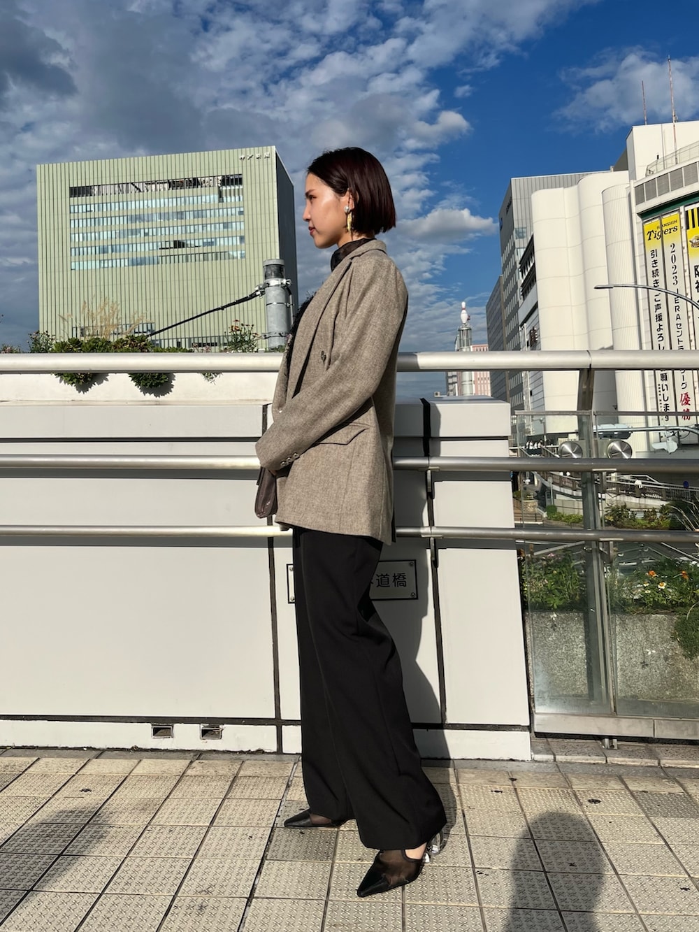 ブラック系のパンプス、シルバー系のハンドバッグ、グレー系のテーラードジャケットを着用したレディースの秋コーディネートの5枚目の写真