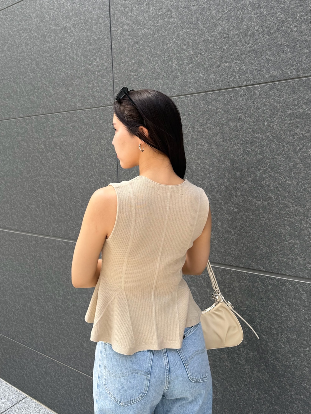 ブルー系のデニムパンツ、ベージュ系のニット/セーター、ホワイト系のハンドバッグを着用したレディースの夏コーディネートの6枚目の写真
