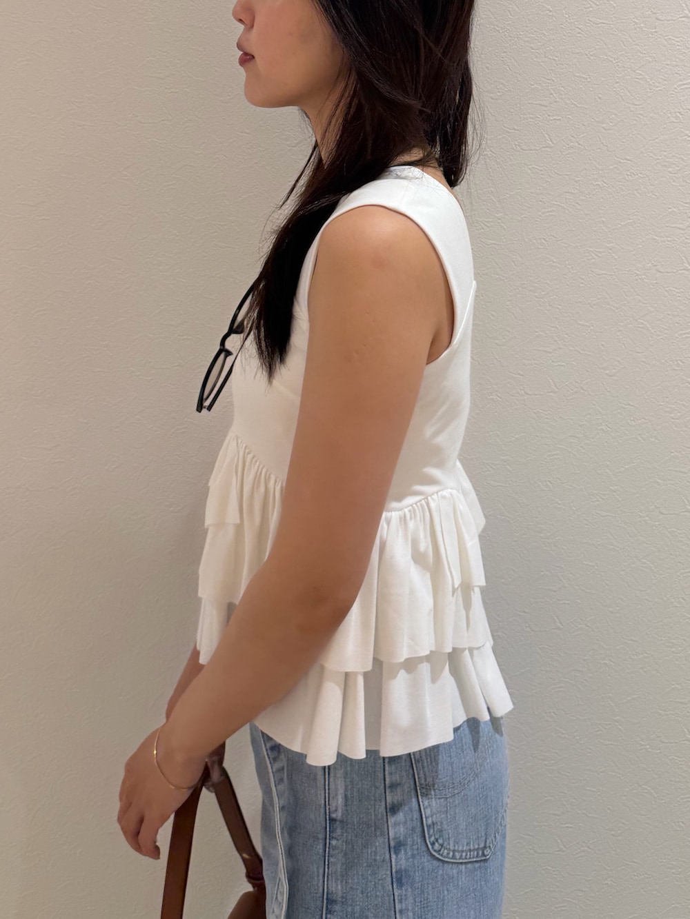 ブルー系のデニムパンツ、ホワイト系のタンクトップ、ブラウン系のハンドバッグを着用したレディースの夏コーディネートの5枚目の写真