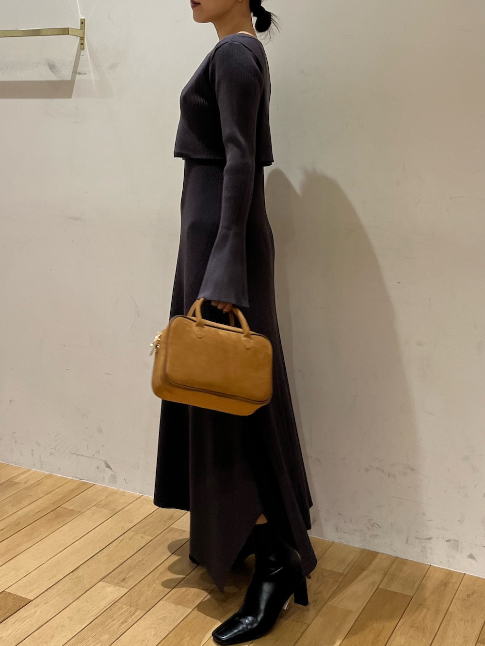 ブラック系のブーツ、グレー系のワンピース、ブラウン系のハンドバッグを着用したレディースの秋コーディネートの2枚目の写真