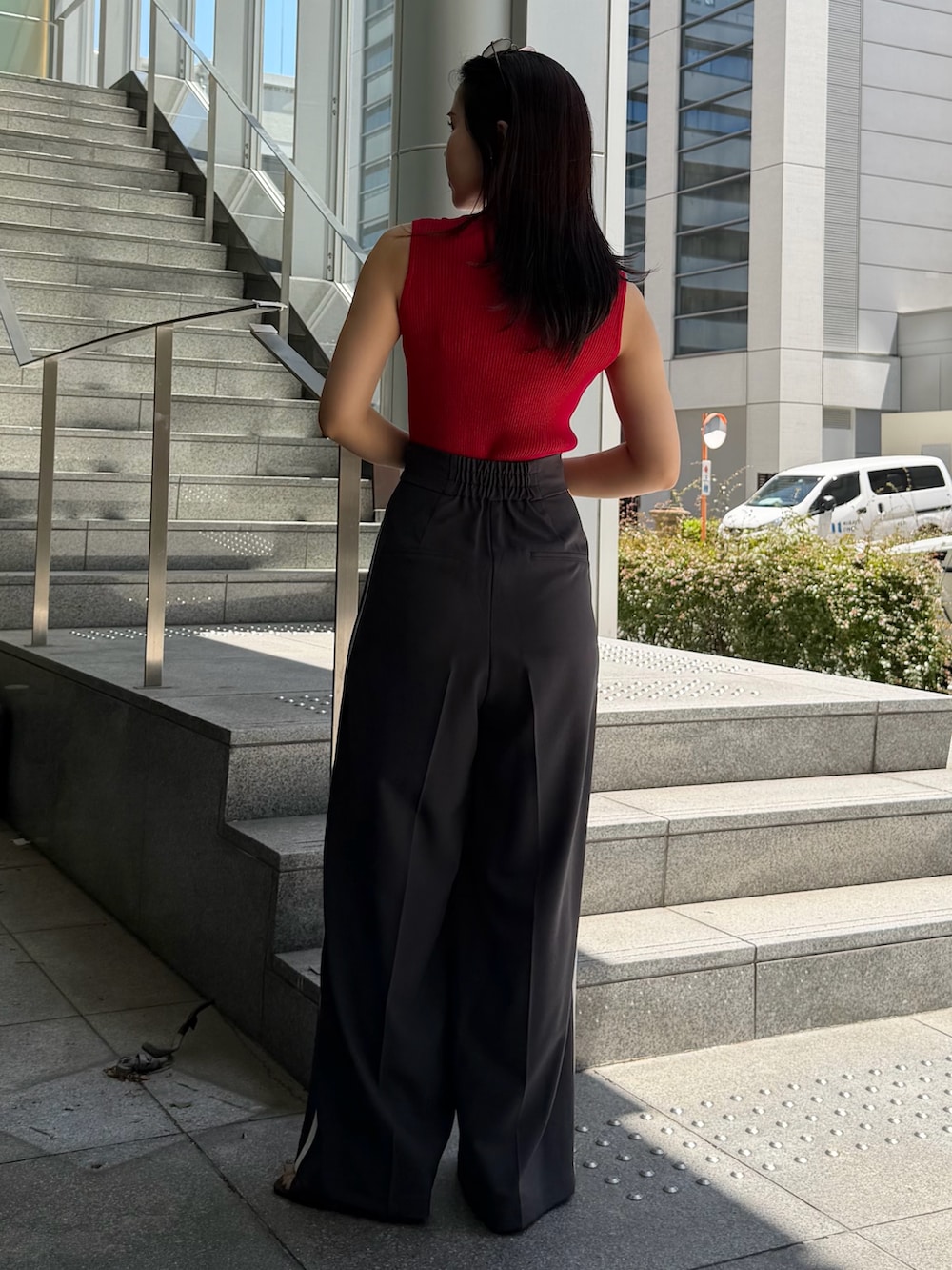 グレー系のその他パンツ、レッド系のニット/セーター、ブラウン系のハンドバッグを着用したレディースの春コーディネートの3枚目の写真